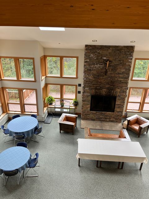 A gathering room with a stone fireplace and tall windows.