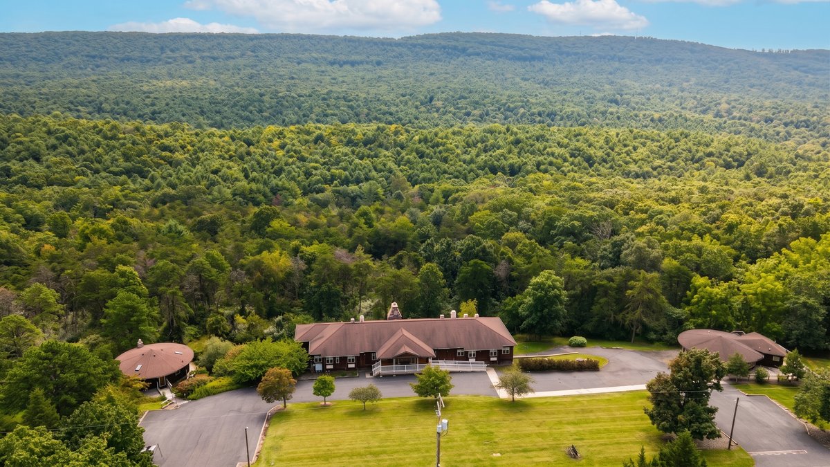 Aerial view of the lodge, circular retreat buildings, and woodland at the former Rising Phoenix